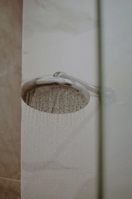 Individu anonyme portant des gants en caoutchouc jaunes utilisant une éponge basique pour laver un miroir dans une salle de bain
